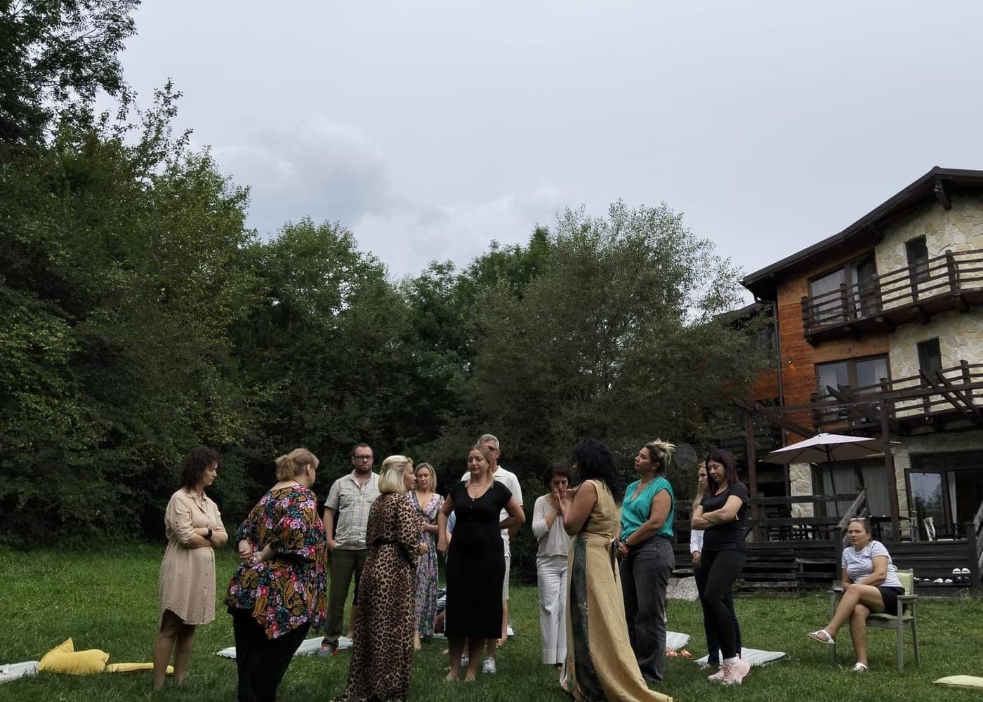 Grup de participanți la un retreat al Academiei Călătorie către Sine, în curtea pensiunii unde are loc evenimentul